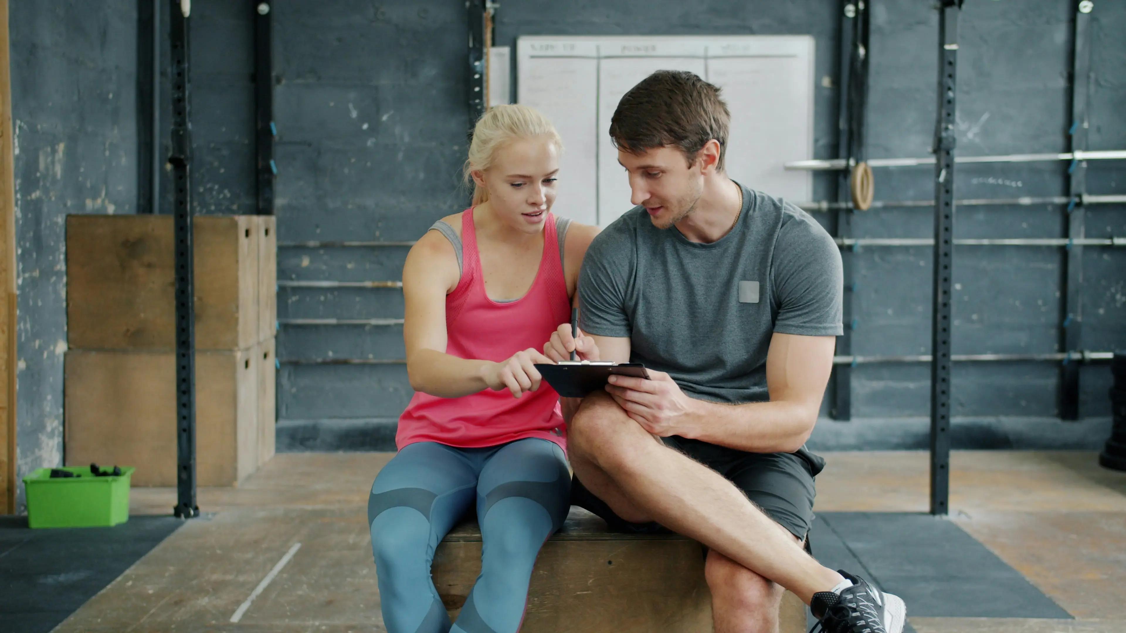 A man and a woman looking at a tablet together in the gym.