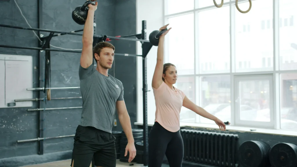 A man and a woman performing kettlebell swings