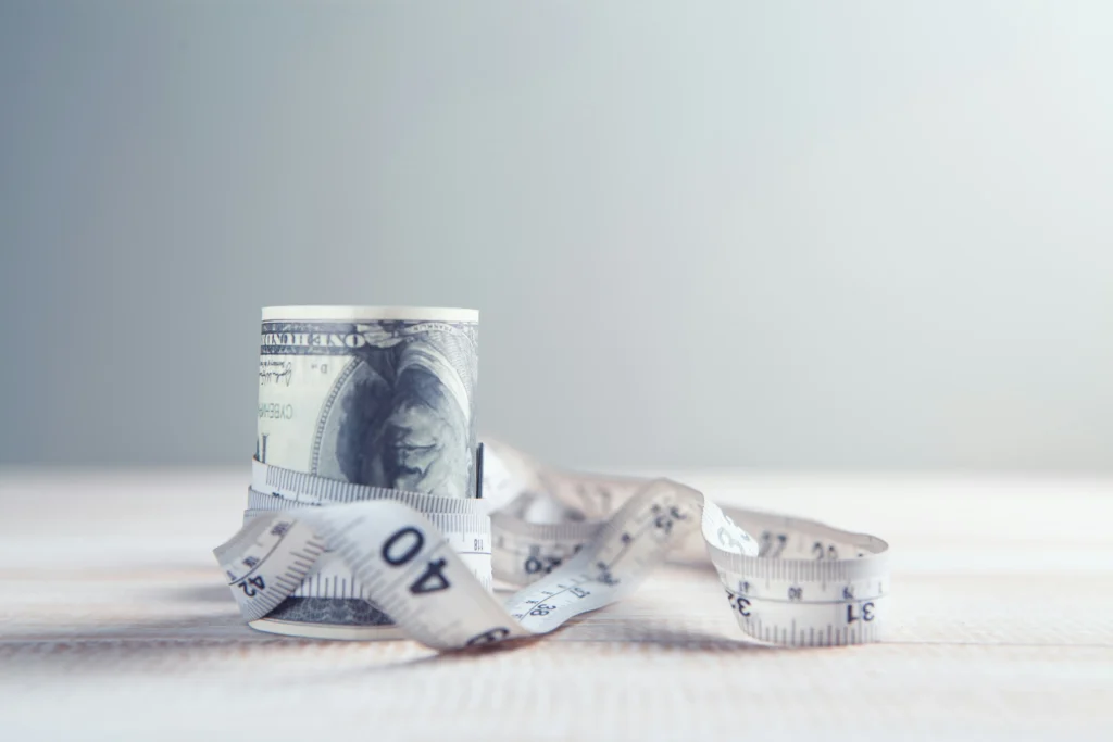 Roll of 100 dollar bills wrapped with measuring tape