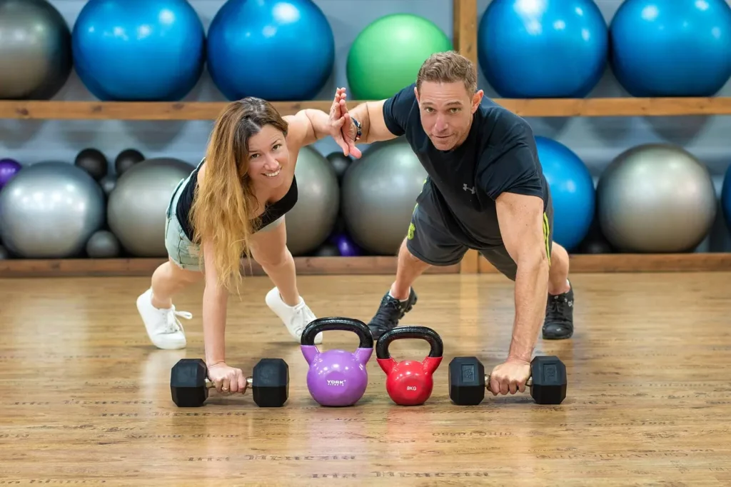 トレーニング中に女性とハイタッチする片腕腕立て伏せのポーズをとる男性