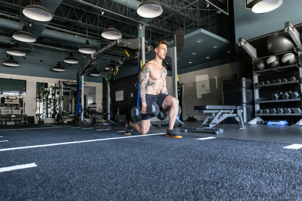 Photo of a man doing one-legged squats with dumbbells in each hand