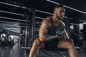 Photo of a man with tattoos on his arms working out at the gym.