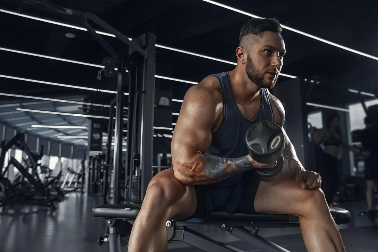 Photo of a man with tattoos on his arms working out at the gym.
