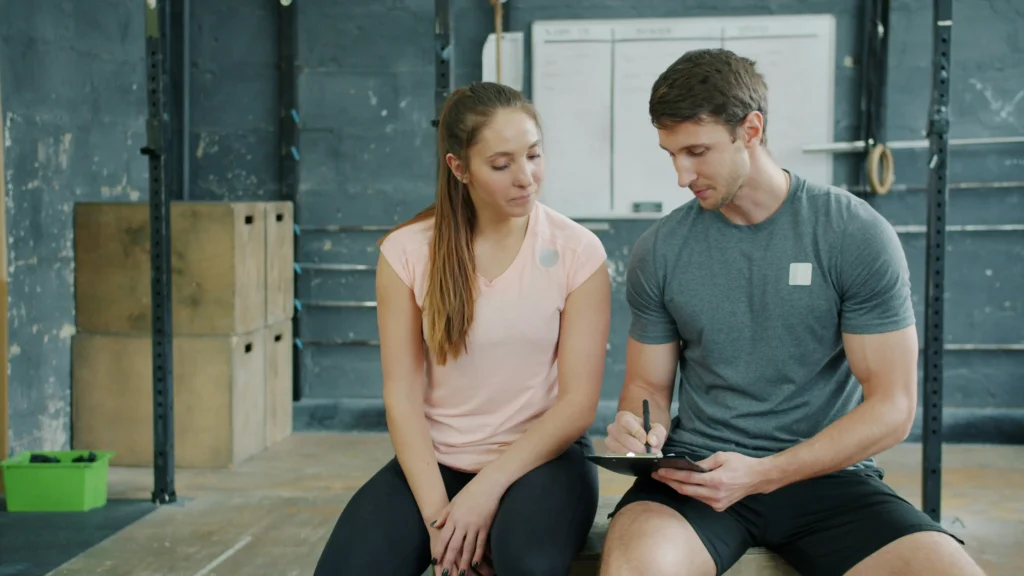 Trainer discussing workout plan with client at gym