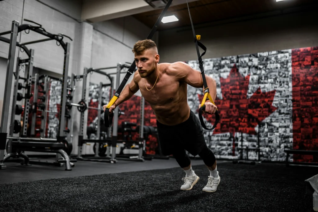 Muscular man training with TRX in a gym
