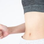 Woman giving a thumbs-up near her waist after dieting at a personal gym in Osaka