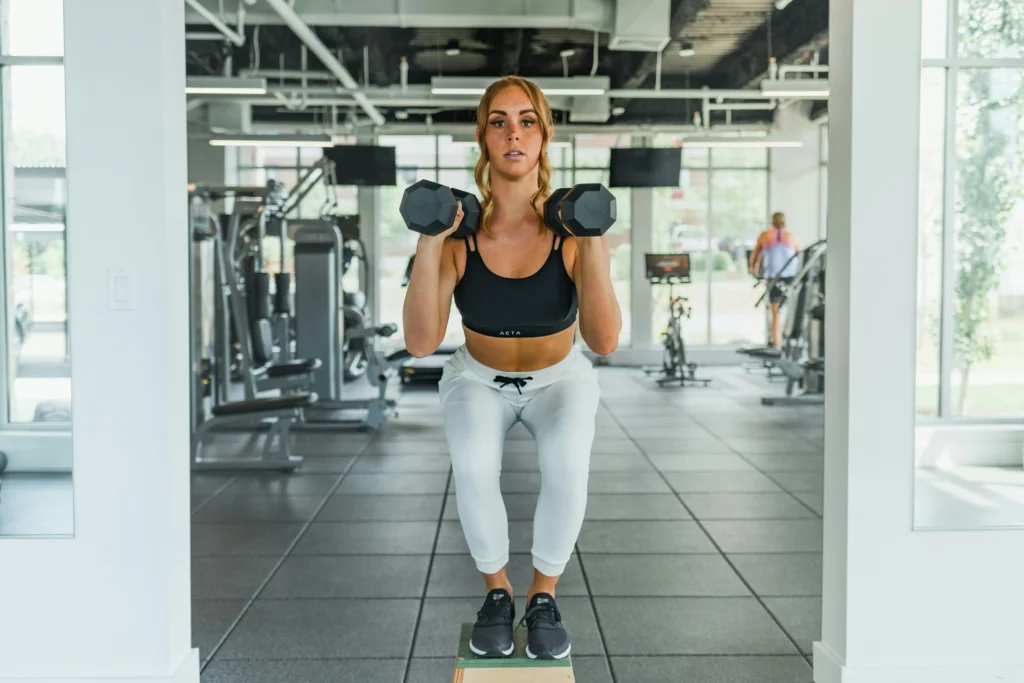 Photo of a woman squatting on blocks with dumbbells
