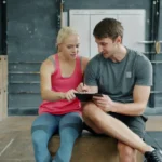 ジムでタブレットを見ている男女