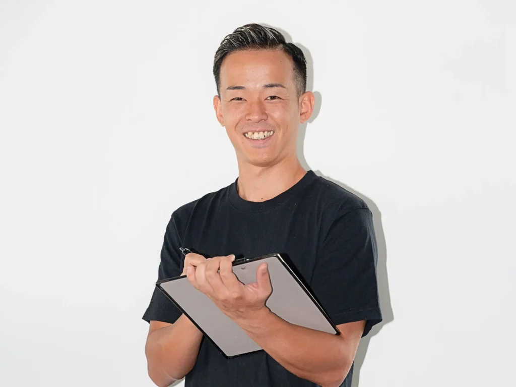 バインダーを持ち、笑顔でヒアリングしながらメモを取るパーソナルトレーナー