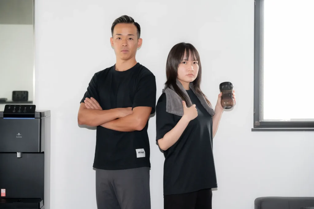 背中合わせで真剣な表情のパーソナルトレーナーとクライアント