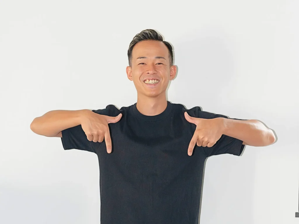 笑顔でジェスチャーしながら人差し指を下に向けるパーソナルトレーナー