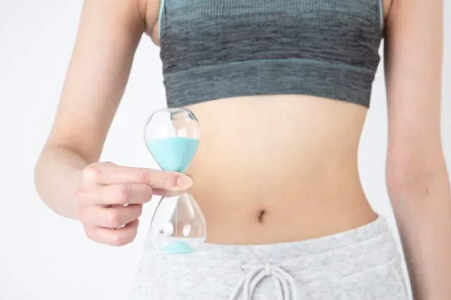 ウエスト周りで砂時計を持っている女性
