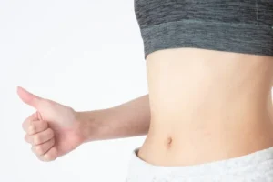 ウエスト周りで親指を上げている女性