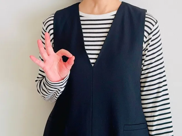 胸元でOKサインをする女性