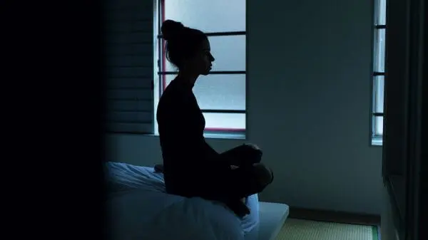 暗い部屋のなかで座っている女性の写真